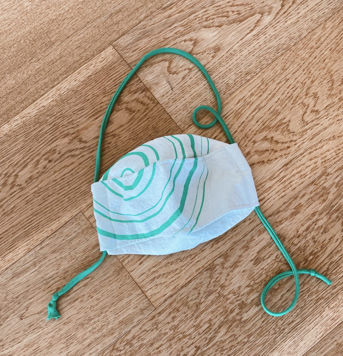 a mask with green circles as a design, laid out on a wood floor