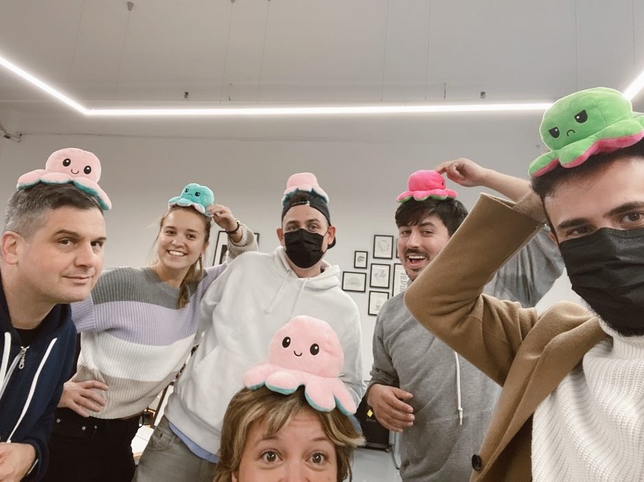 group of 5 people smiling with an octopus plushie on their heads.